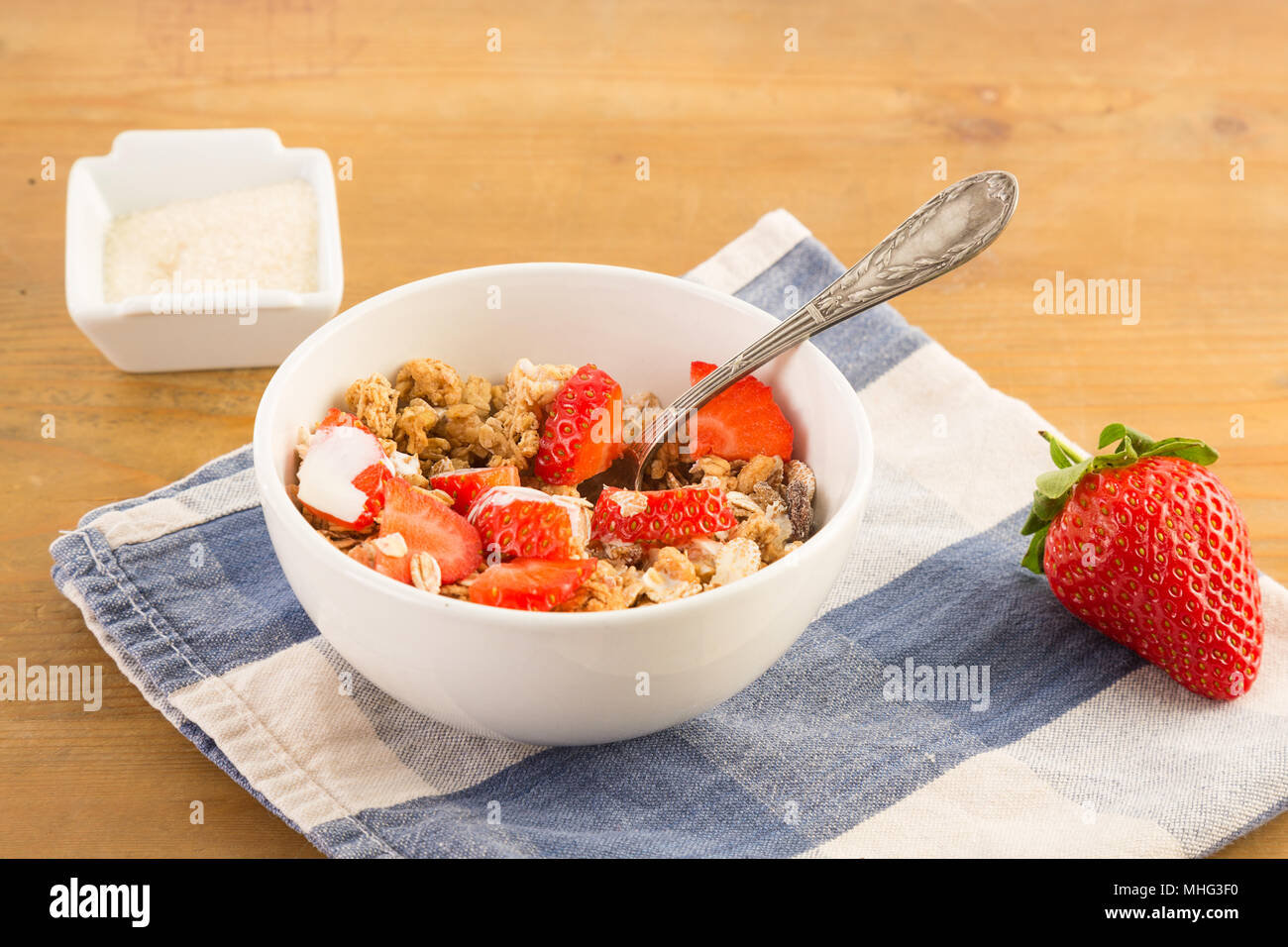 Schüssel Müsli mit Erdbeeren ruht auf einem blau serviette auf einem Holztisch Stockfoto