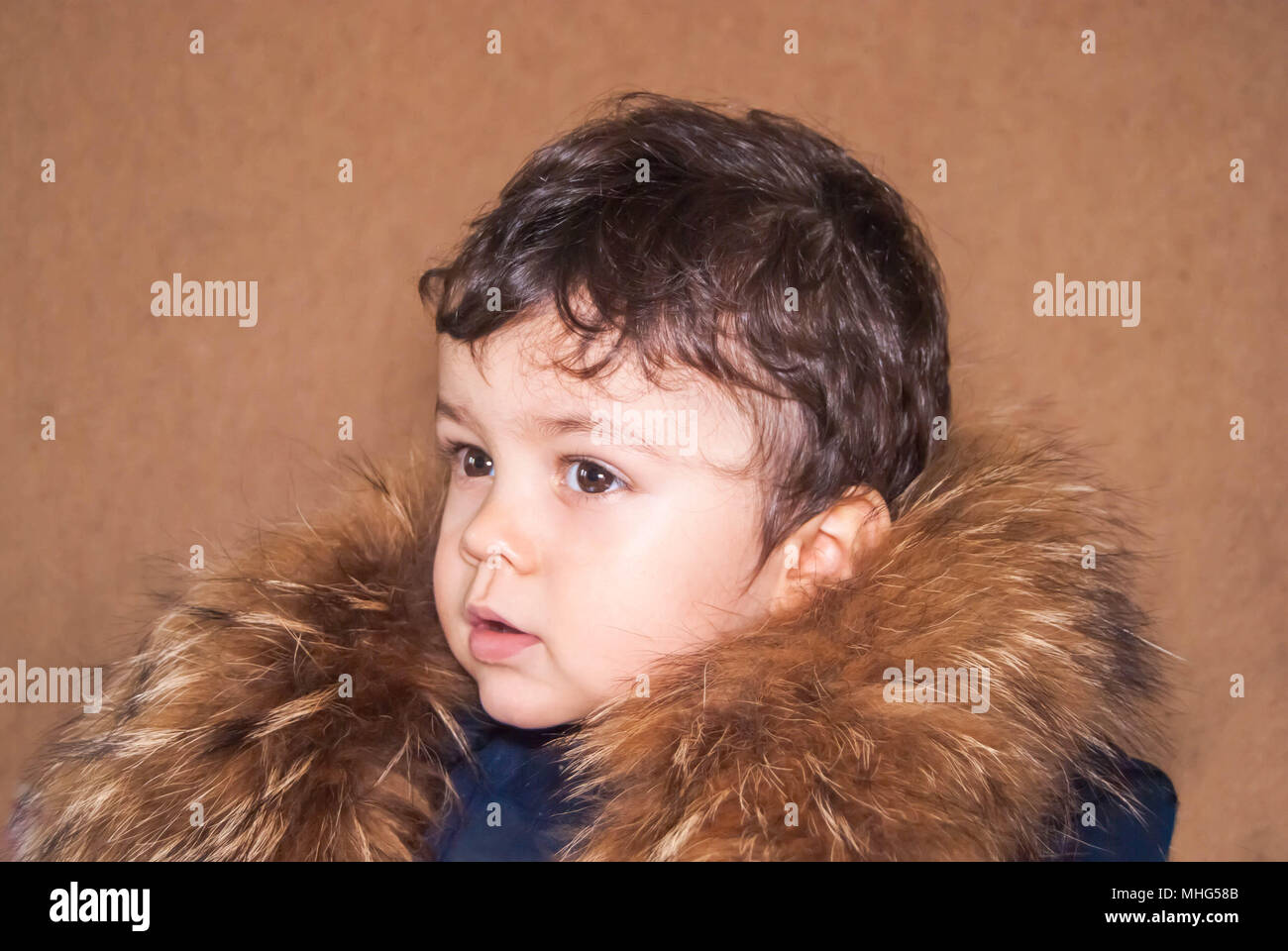 Süße kleine Junge in einer Haube mit natürlichen Fuchs Fell und Waschbär. Stockfoto