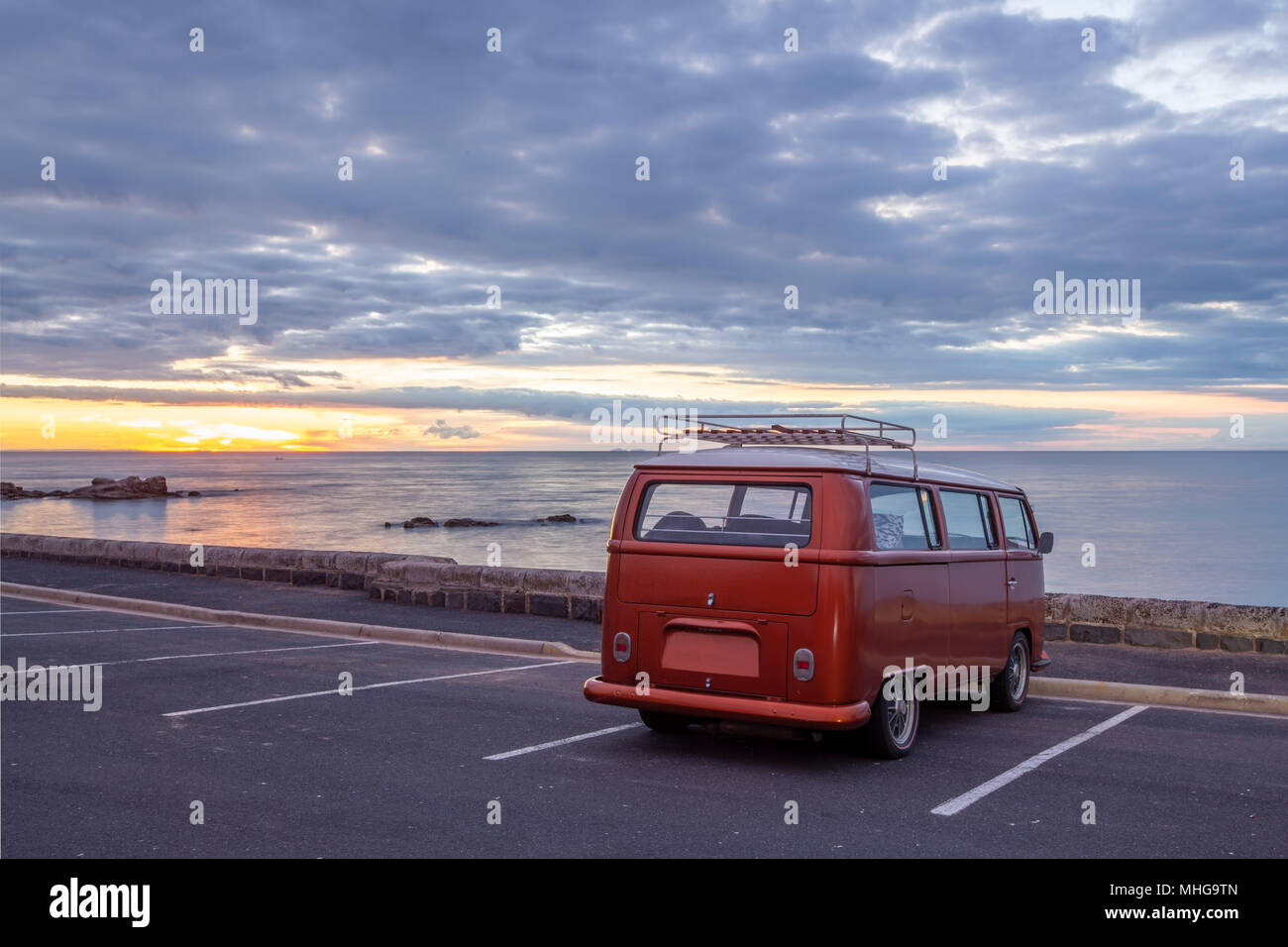 Alte vintage Minivan auf leeren Parkplatz direkt am Wasser geparkt bei Sonnenuntergang Stockfoto