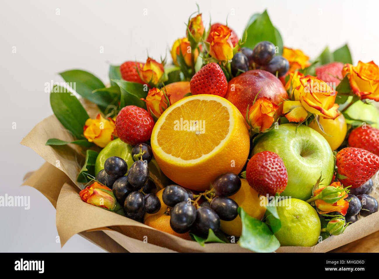 Helle Blumenstrauß aus Äpfeln, Orangen, Erdbeeren, Trauben, Pflaumen und Blumen Garten Rosen als Geschenk Stockfoto