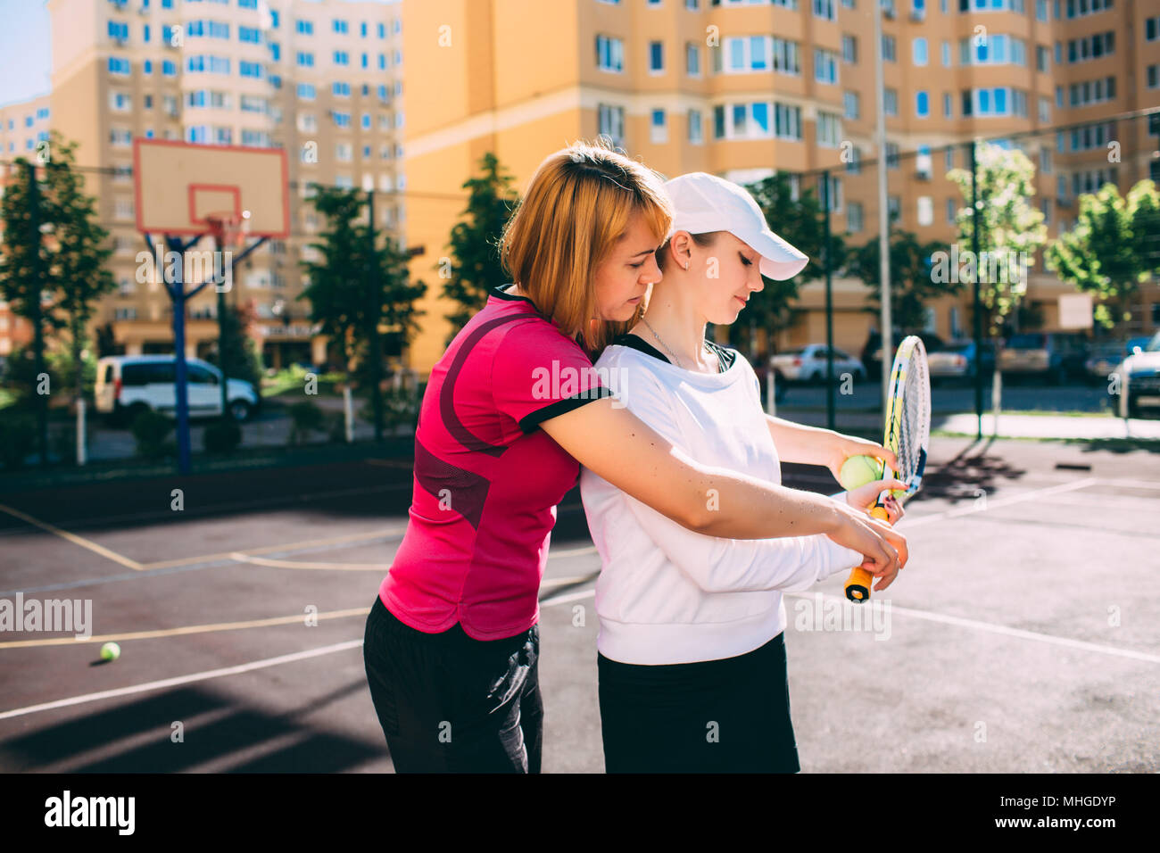 Tenniskurs. Einer jungen Frau beim Tennisspielen beibringen, während sie an einem sonnigen Tag auf dem Tennisplatz der Stadt steht Stockfoto