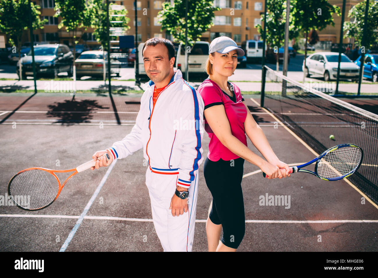 Zwei lächelnde Tennisspieler holding Tennisschläger, vor dem Beginn des Set, stehend auf dem städtischen Tennisplatz Stockfoto