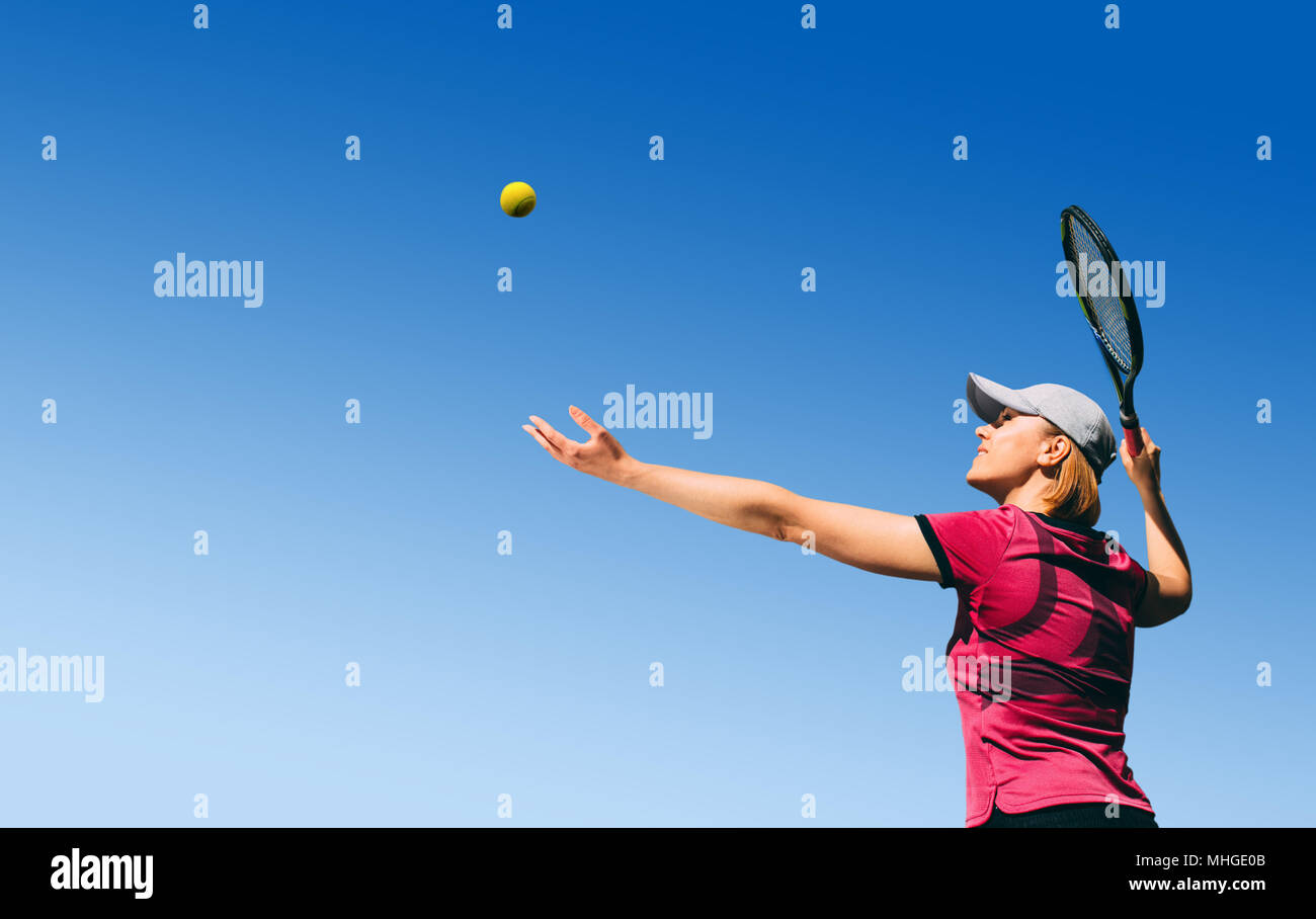 Ansicht von unten junge Frau, tennis player Tennis spielen, den Ball auf blauen Himmel mit leeren Raum serviert. Stockfoto