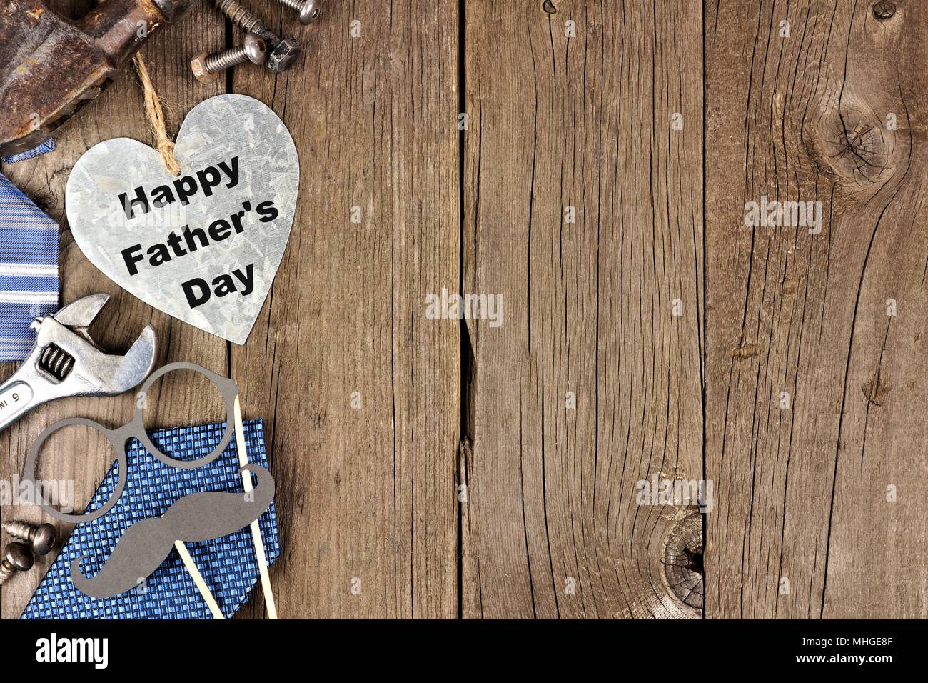 Happy Vatertag metallische Herz mit seitlichen Grenze von Werkzeugen und Beziehungen auf einer hölzernen Hintergrund Stockfoto