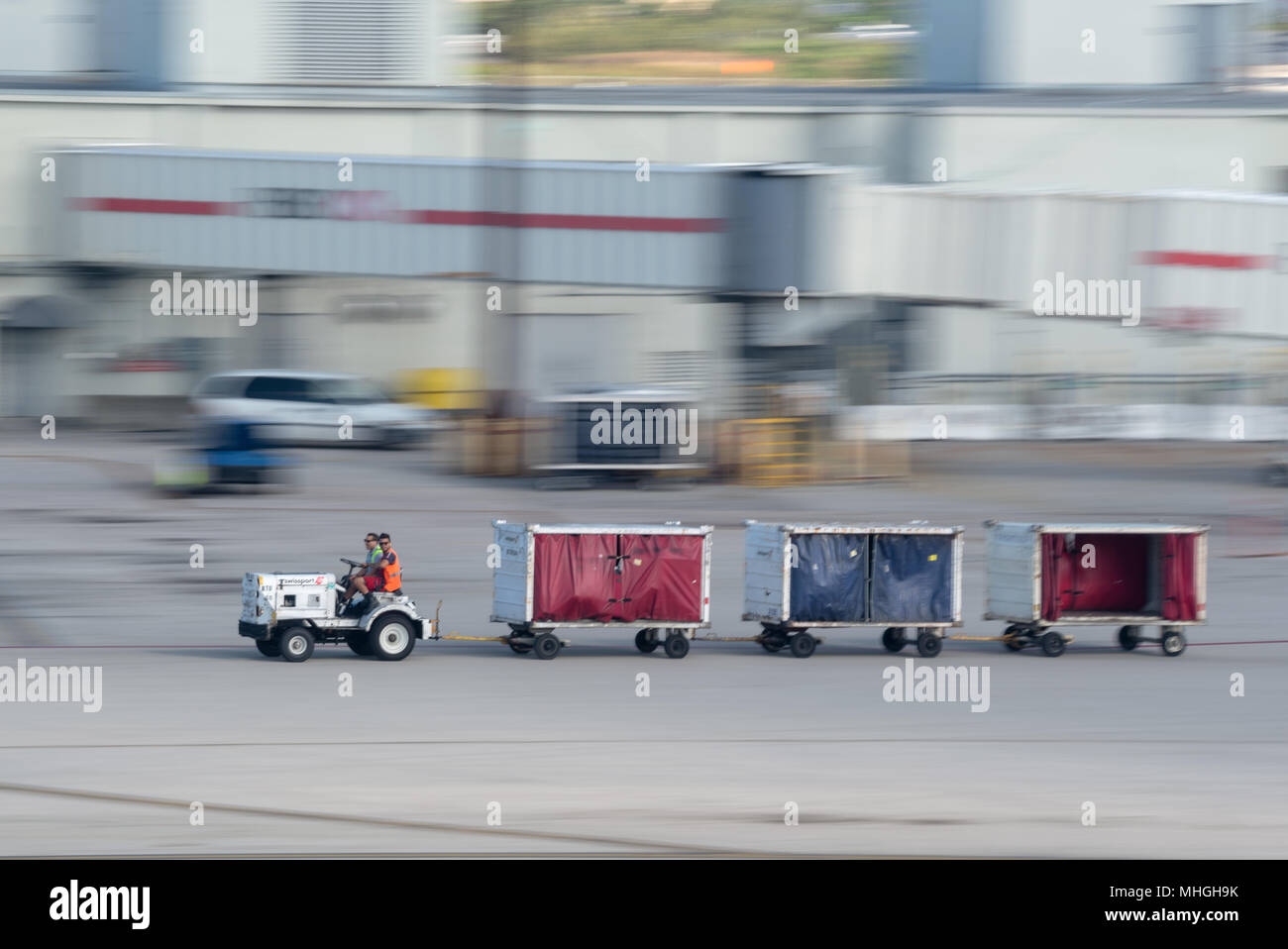 Bodenpersonal ein Gepäck Traktor auf der Rollbahn am Miami International Airport in Miami, Florida. Stockfoto