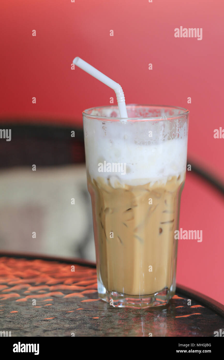 Cool Kaffee in ein Glas mit einem weißen Rohr auf ein Lebensmittel Tabelle im Coffee Shop. Stockfoto
