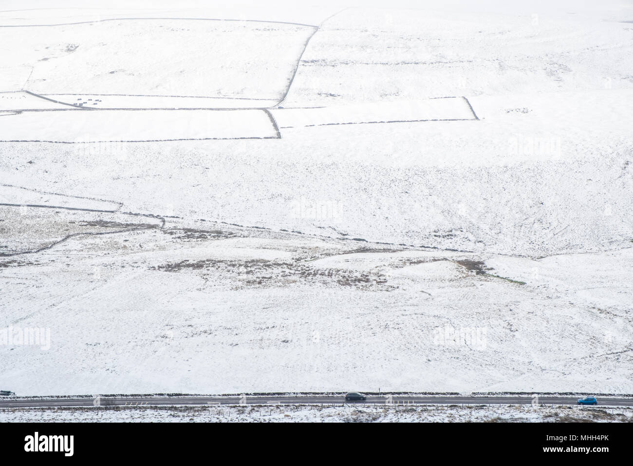 Autos auf einer Straße neben schneebedeckten Hügel Felder bei Peakshill in der Landschaft, Derbyshire Peak District, Großbritannien, Großbritannien Stockfoto