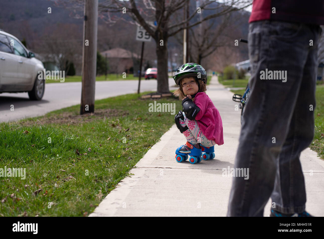 Kleinkind Mädchen mit Knie- und Ellenbogenschützer, Skates auf. Stockfoto