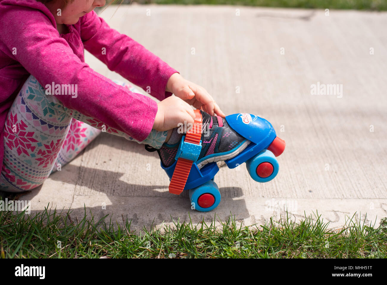 Kleinkind Mädchen mit Knie- und Ellenbogenschützer, Skates auf. Stockfoto