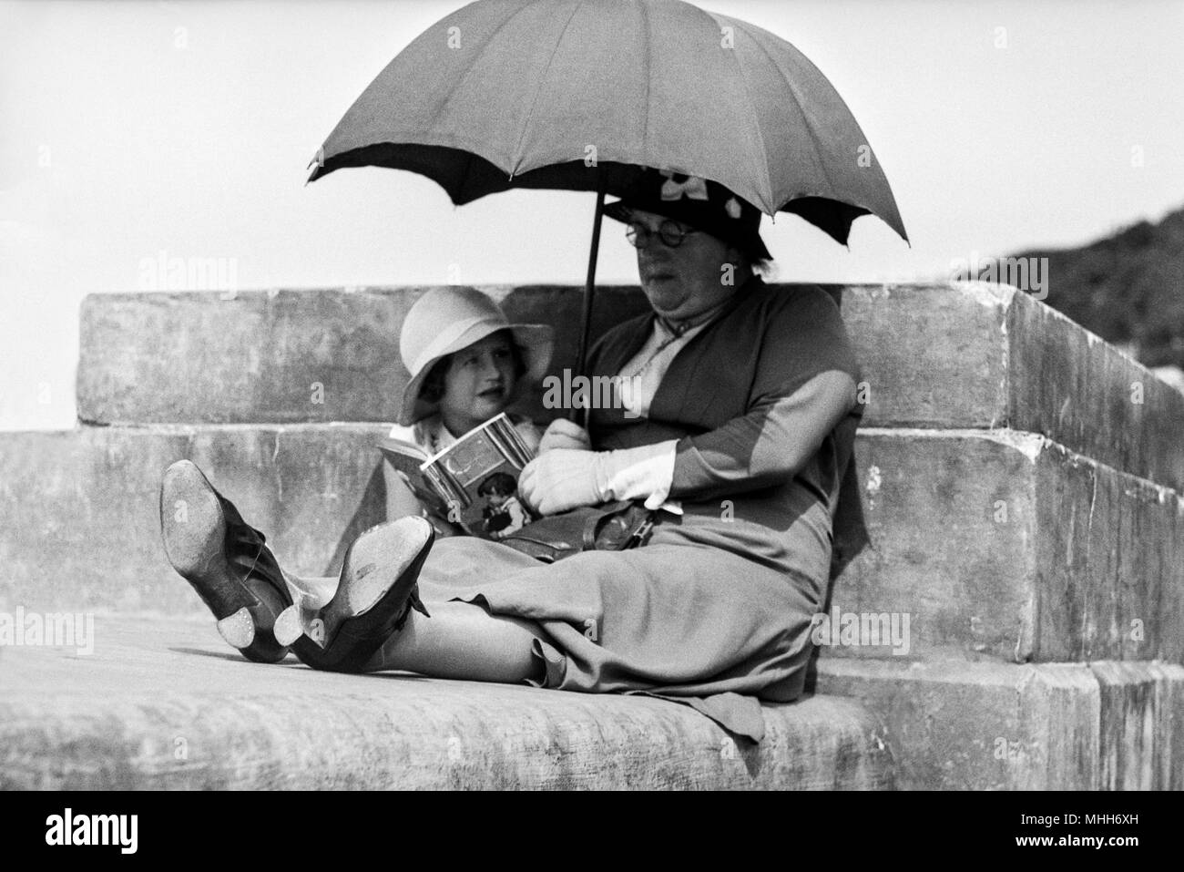 Ältere Frau mit einem Buch zu einem jungen Mädchen ca. 1930 s Stockfoto