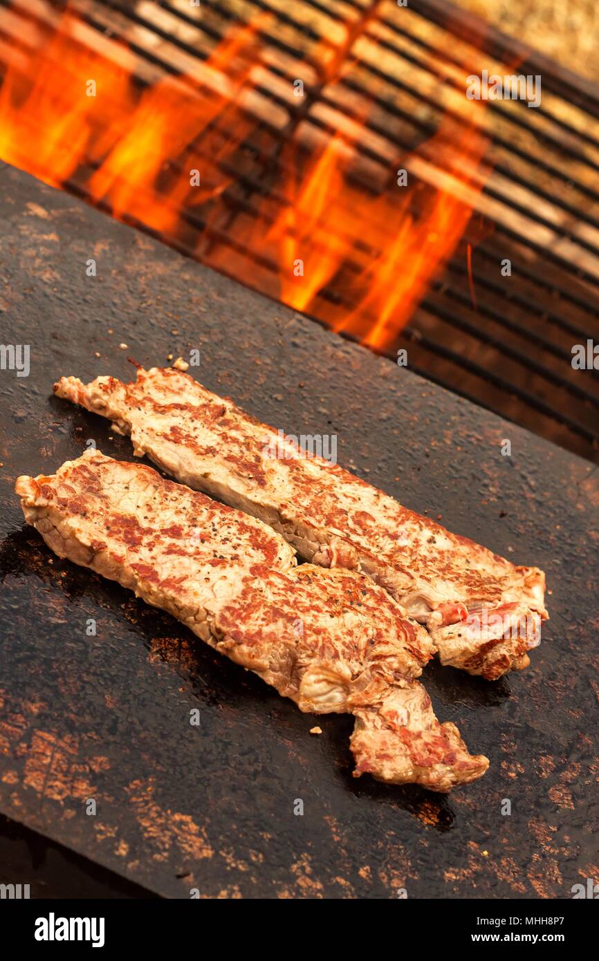 Grillen beef steak auf einer Granitplatte. Zubereitung von Fleisch auf  Feuer. Sommer Grill Stockfotografie - Alamy