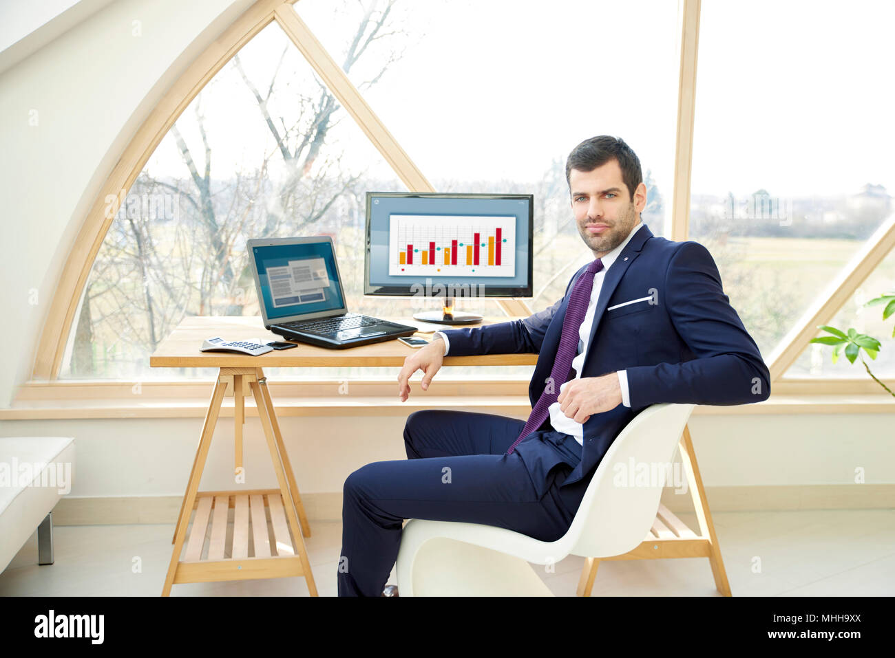 Portrait von zuversichtlich finanzielle Investitionen Geschäftsmann sitzen vor dem Laptop während der Arbeit auf die finanzielle Berichterstattung. Stockfoto