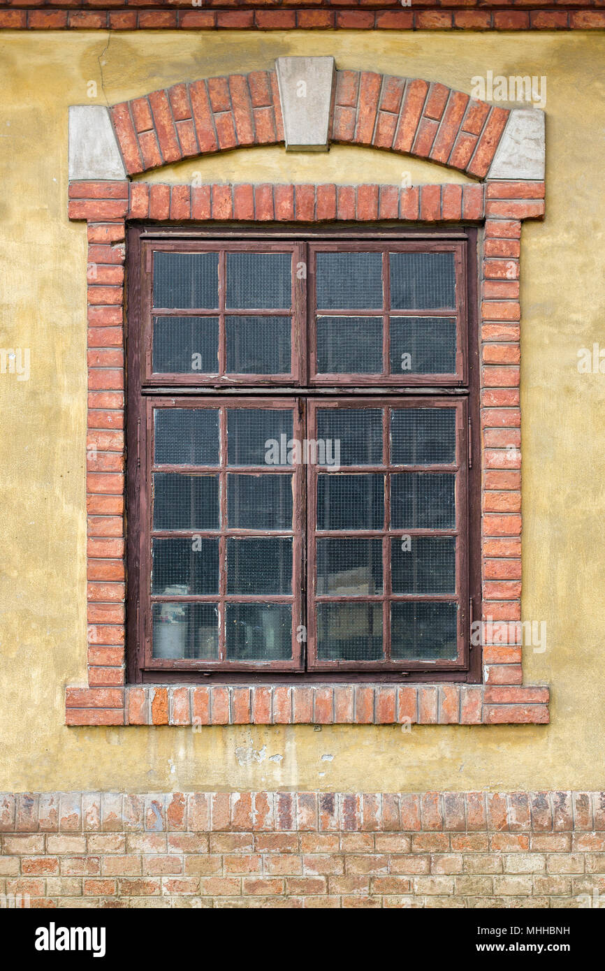 Alte Fenster auf gelben Fassade, mit dekorativen Backstein Rahmen und Arch Stockfoto