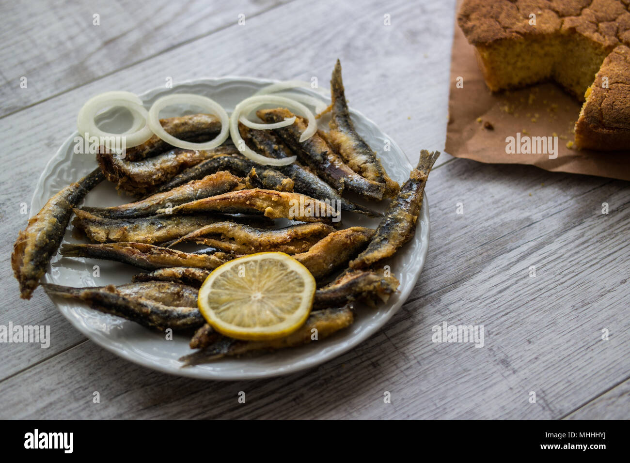 Türkische Hamsi Tava mit Cornbread/Frittierte Sardellen auf weißem Holz- Oberfläche. Stockfoto