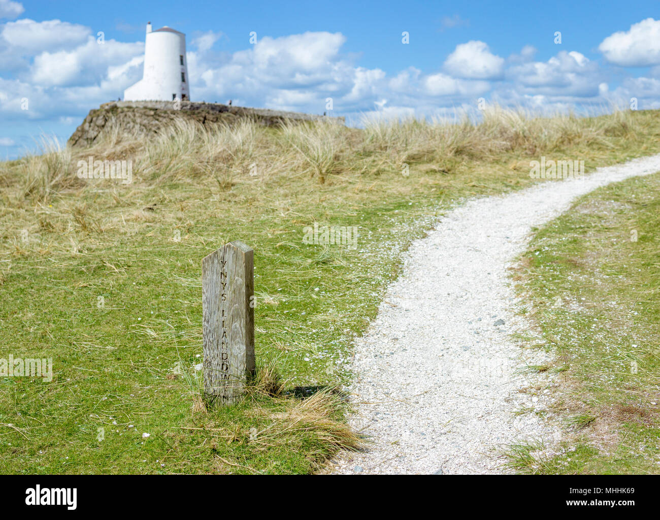 Ynys Llanddwyn marker Post im Fokus mit Twr Mawr Leuchtturm im Hintergrund auf llanddwyn Insel Anglesey. Stockfoto