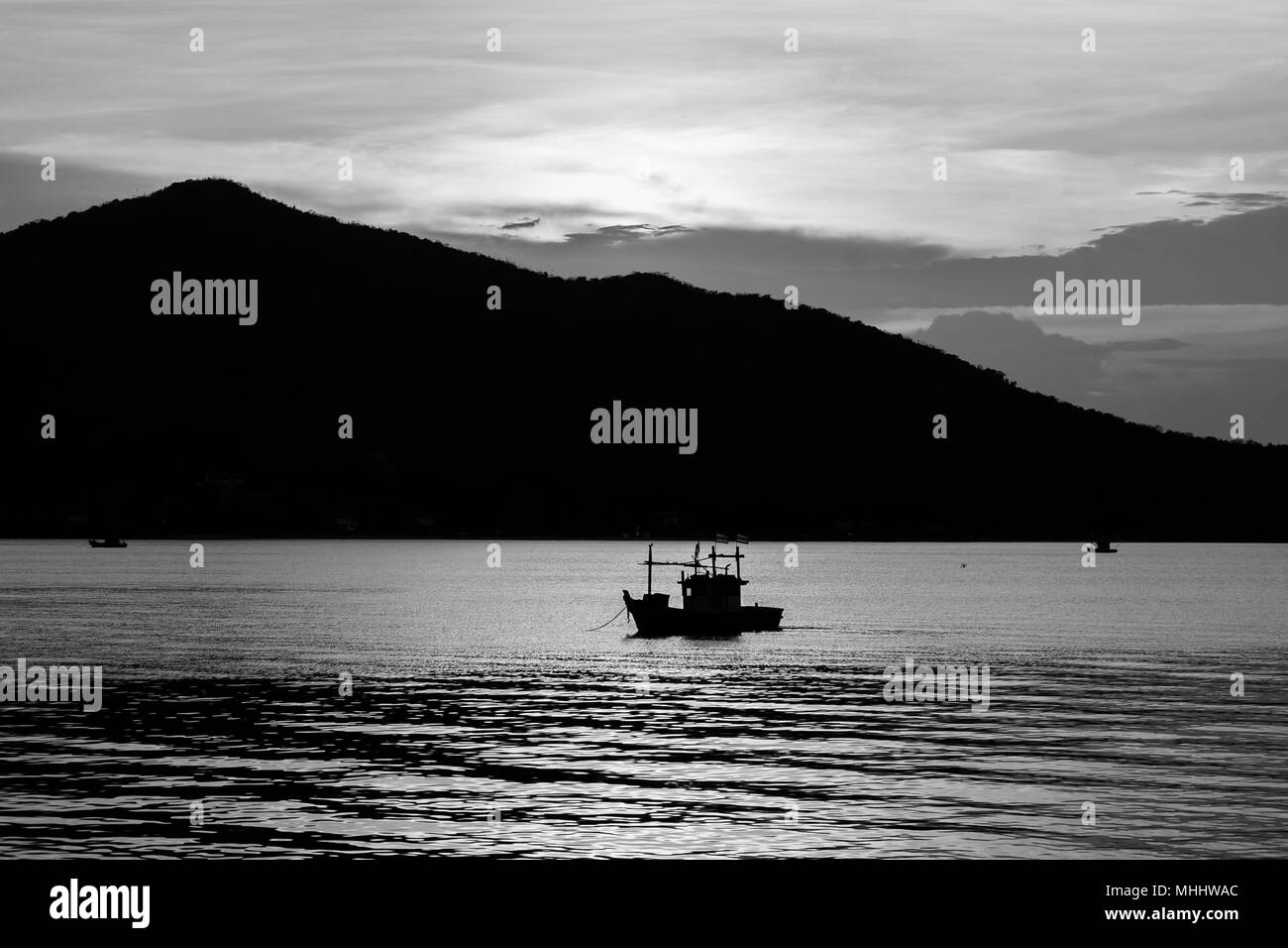 Abstrakte schwarz-weiß Bild schöne Seascape Blick auf silhouette Fischerboot auf dem Meer mit Sonnenuntergang Licht im Hintergrund. Stockfoto