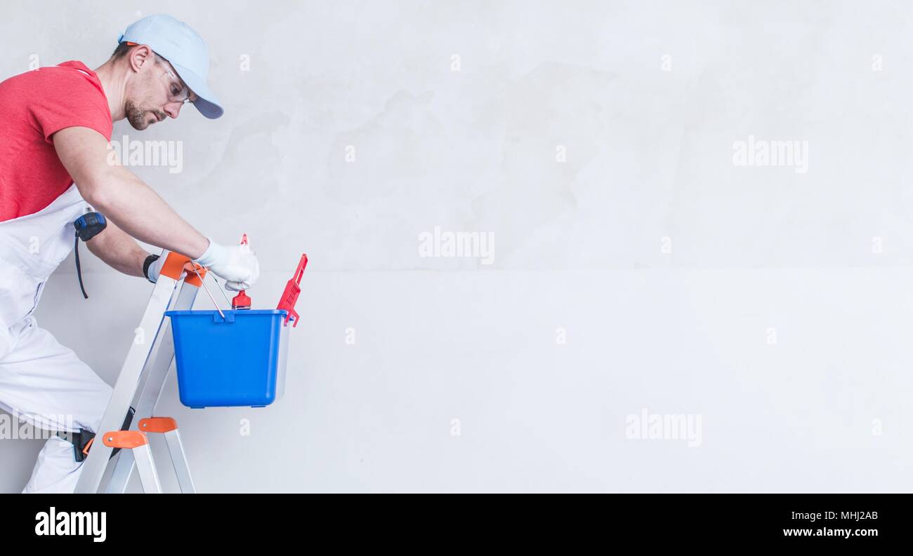 Maler Kopieren Raum Foto Konzept mit Platz kopieren. Kaukasische Malerei Arbeiter auf dem kleine Metallleiter. Stockfoto