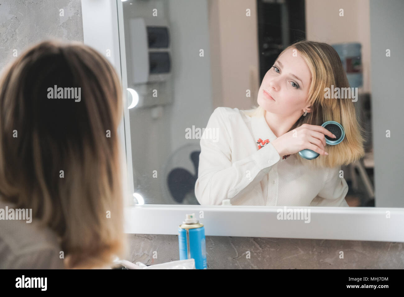 Schöne junge Frau vor dem Spiegel ihr Haar bürsten Stockfoto