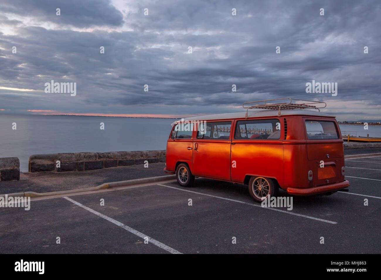 Retro orange Van auf dem Ozean Strand bei Sonnenuntergang Stockfoto