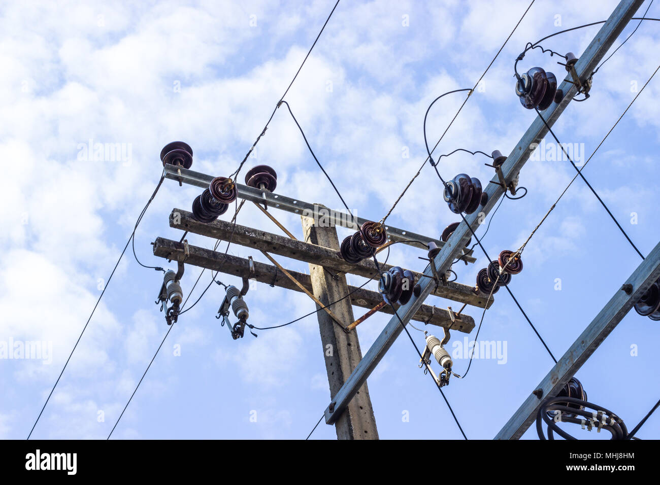 Elektrische Pole anschließen, um die Spannung der elektrischen Kabel an gegen strahlend blauen Himmel Stockfoto