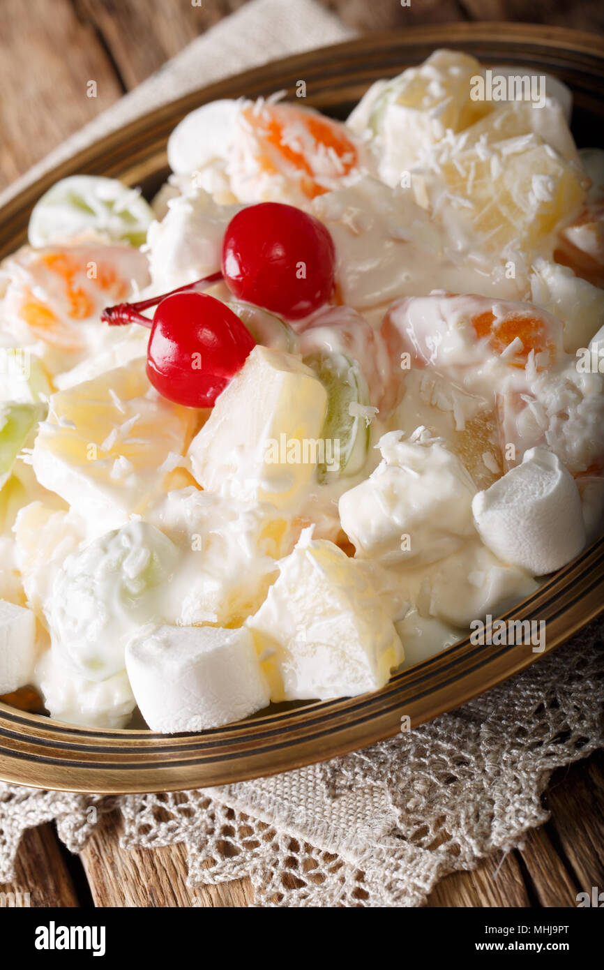 Obstsalat Ambrosia aus Ananas, Mandarinen, Weintrauben und marshmelow Close-up auf einem Teller. Vertikale Stockfoto