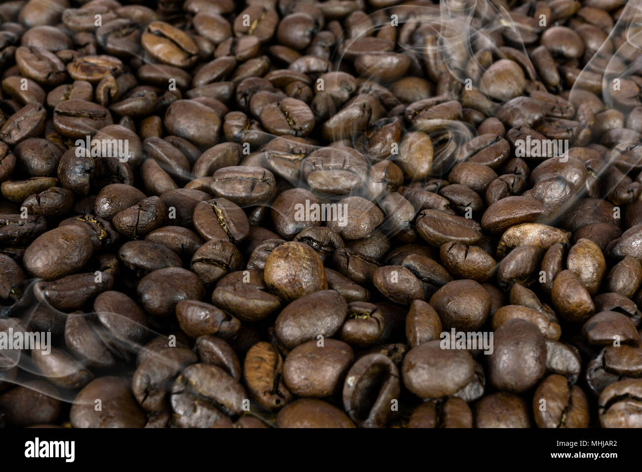 Die kaffeeproduktion Hintergrund - viele heiße braune Bohnen geröstet und Rauch in Nahaufnahme als Textur (Details). Stockfoto
