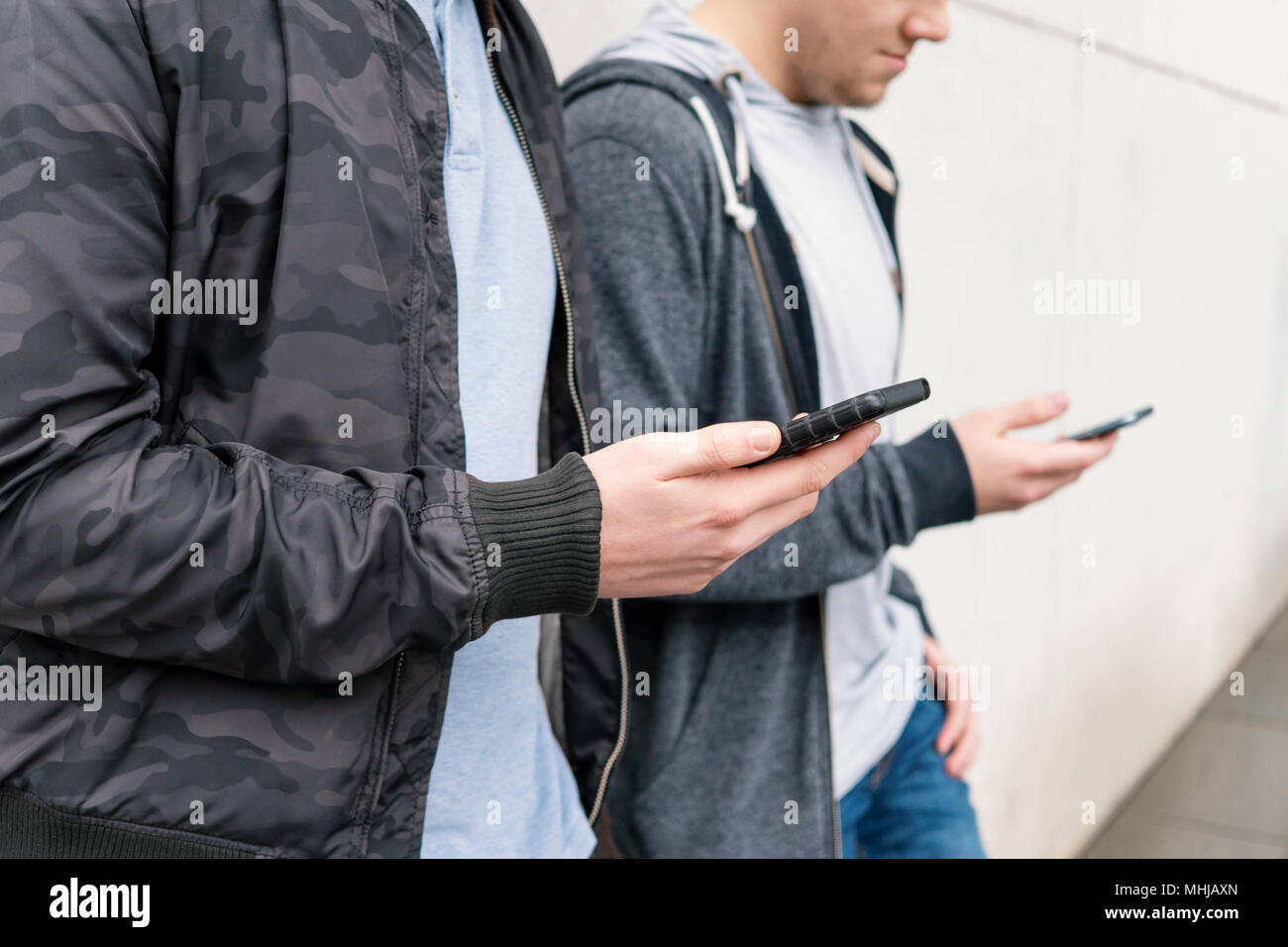 Zwei antisoziale Handy süchtig männliche Jugendliche mit Smartphone, Technik Konzept, lehnte sich gegen die Wand mit Kopie Raum Stockfoto
