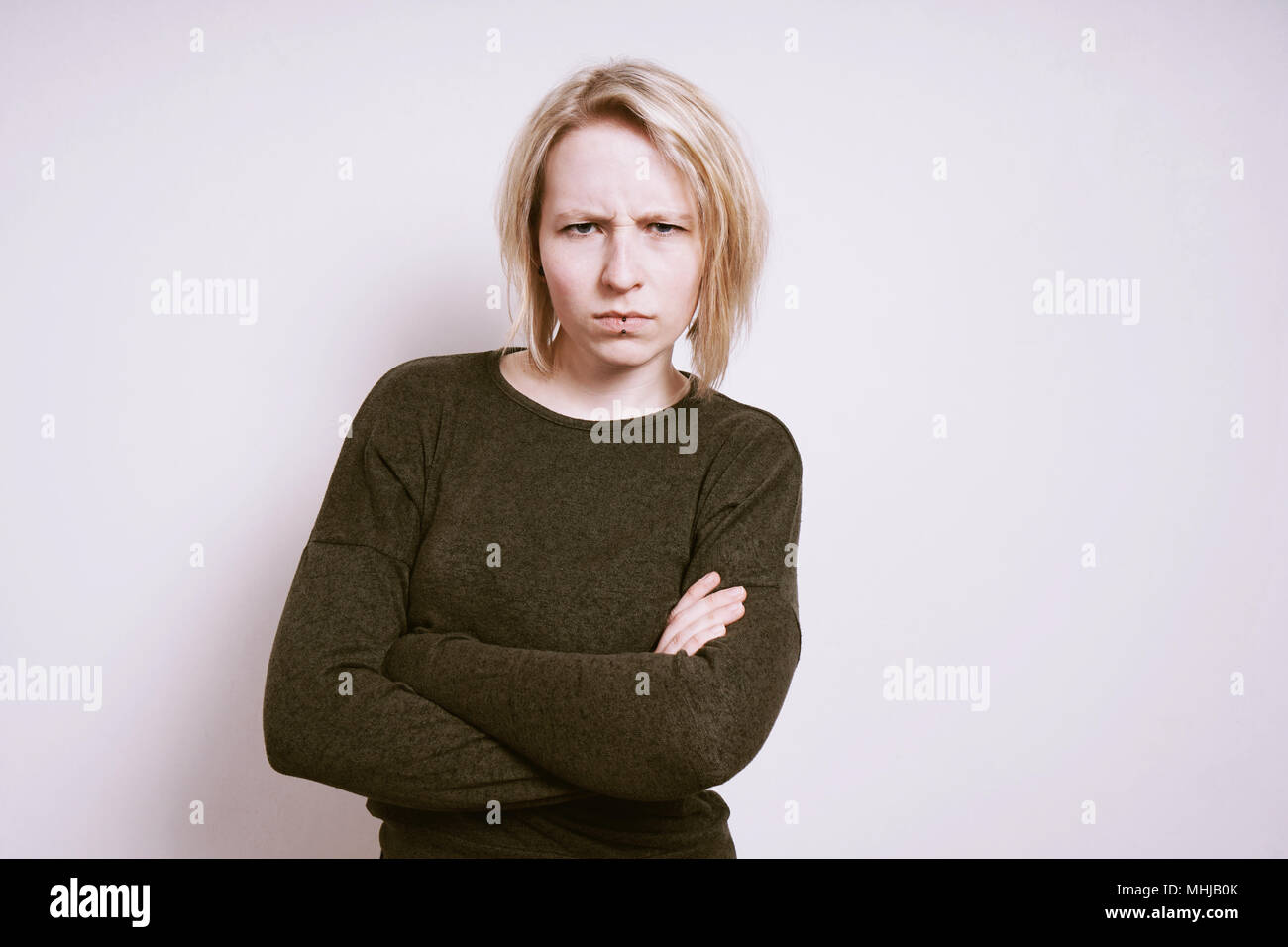 Zornige junge Frau runzelte mit verschränkten Armen, negative Emotionen Konzept mit Kopie Raum Stockfoto