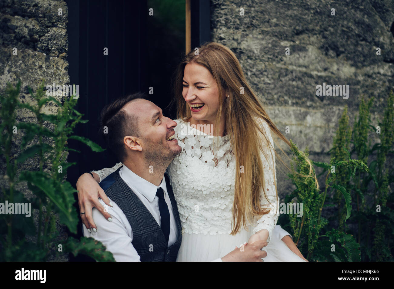 Junge stilvolle Mode Paar in Liebe in Island. Frau und Mann umarmen und möchten einander zu küssen. Stein Berge und isländischer Haus im Hintergrund. Stockfoto