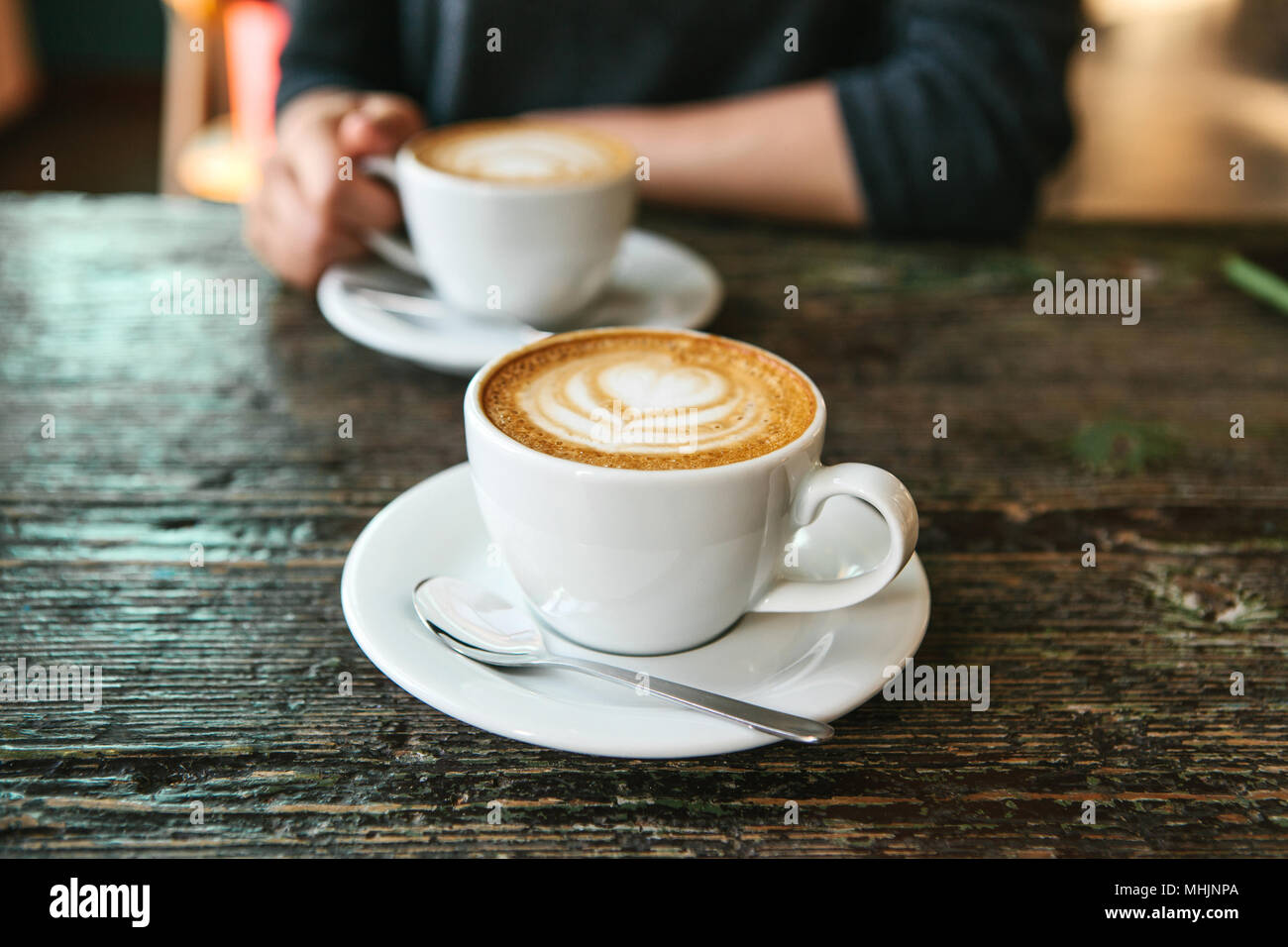 Zwei Tassen Kaffee Auf Einem Holztisch Die Madchen In Ihrer Hand Eine Tasse Kaffee Im Hintergrund Halt Ein Foto Zeigt Ein Treffen Von Menschen Und Einem Gemeinsamen Zeitvertreib Stockfotografie Alamy