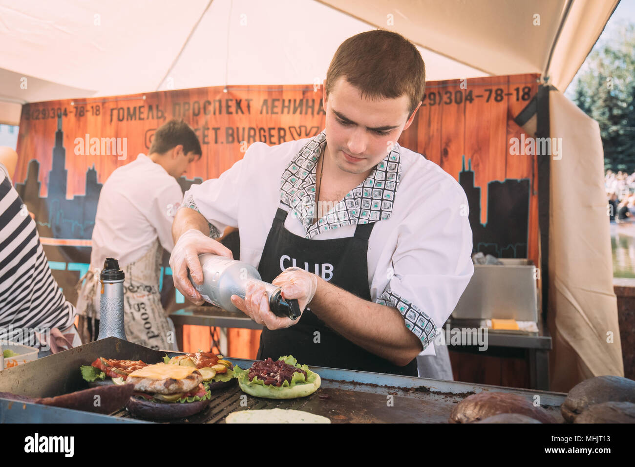 Gomel, Belarus. Mann Kochen Burger auf gastronomische Festival City Essen im Sommer Tag. Stockfoto
