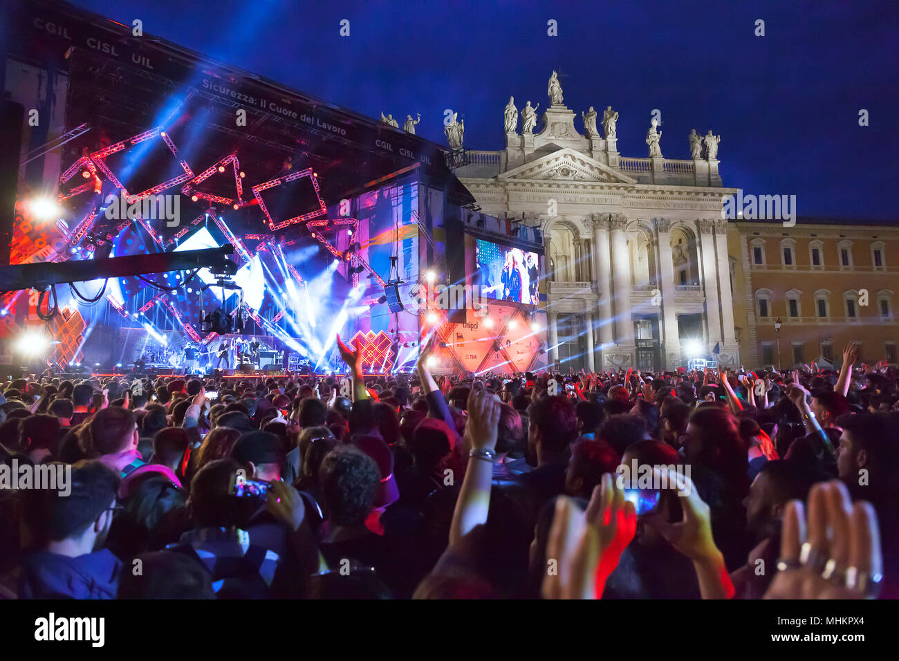 Rom, Italien, 01.Mai 2018: die Bühne des Konzert des ersten Mai, in der Piazza San Giovanni mit seinem bunten Lichter, die grosse Leinwand und die Menge der Fans, im Hintergrund die wunderschöne Basilika San Giovanni in Laterano. Credit: Gennaro Leonardi/Alamy leben Nachrichten Stockfoto