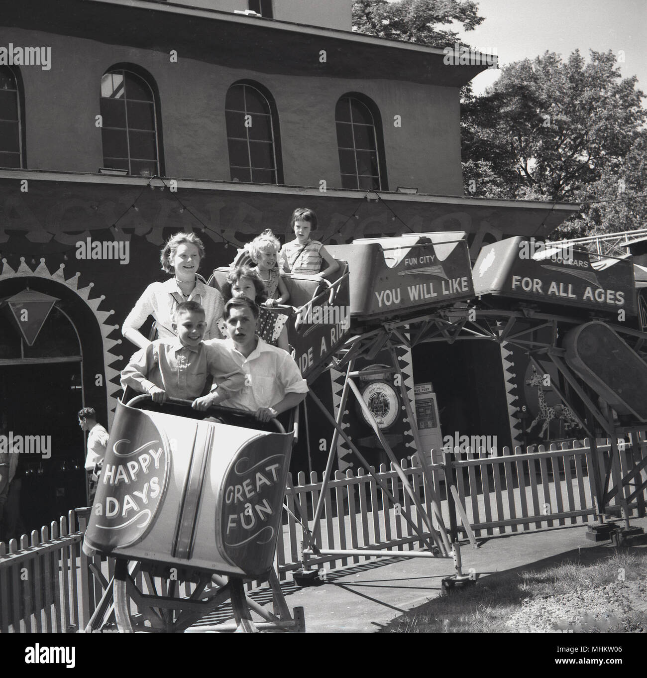 1960, historische, Mutter und Kinder geniessen Sie eine Fahrt im offenen Wagen auf einem 'Achterbahn' im Freien an der Battersea Kirmes, London, England, UK. Stockfoto