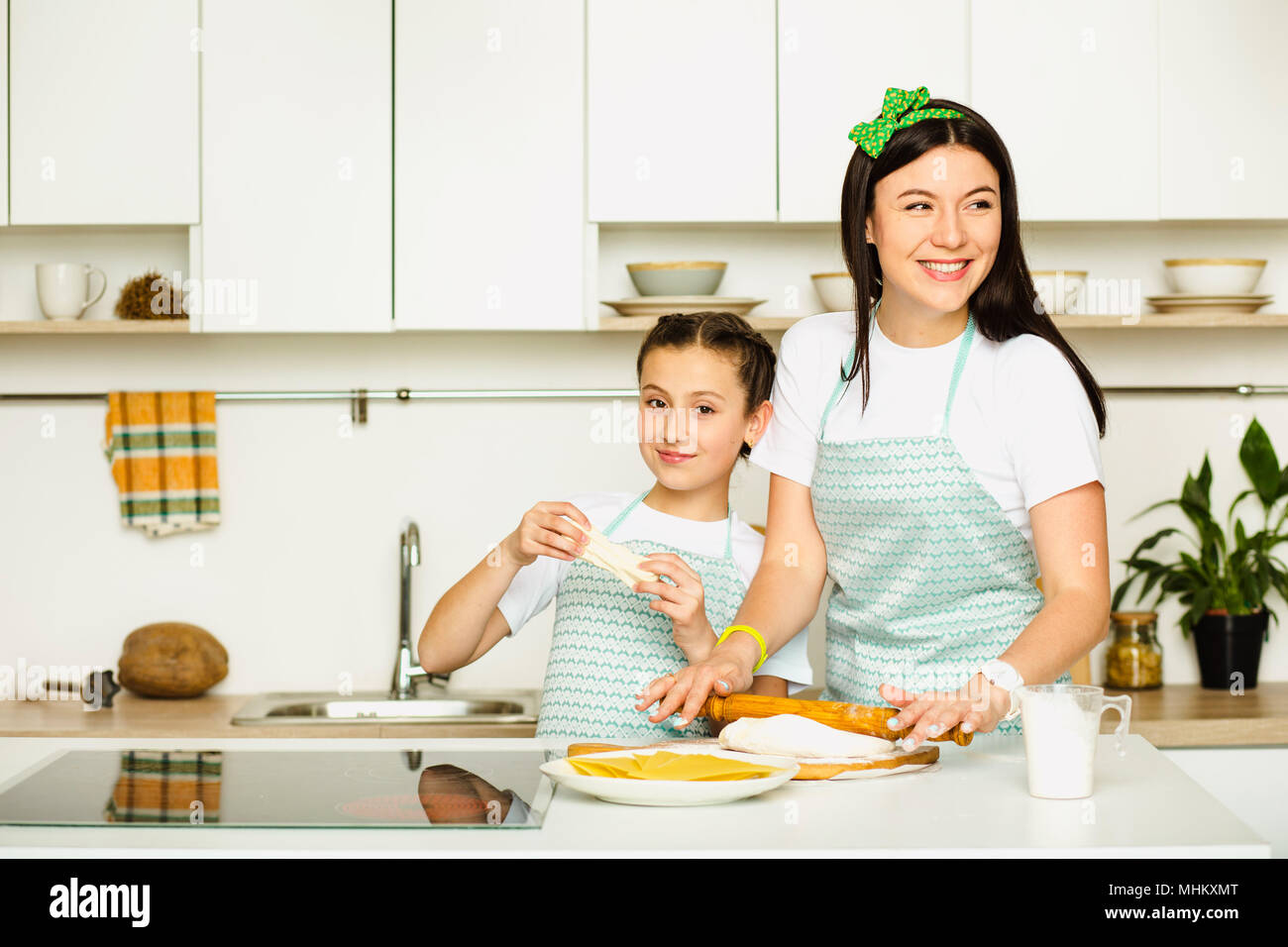 Mehl und machen Spaß für einige köstliche Speisen. Schuss ein hübsches Mädchen Spaß Backen mit ihrer Mutter am weißen Küche Stockfoto