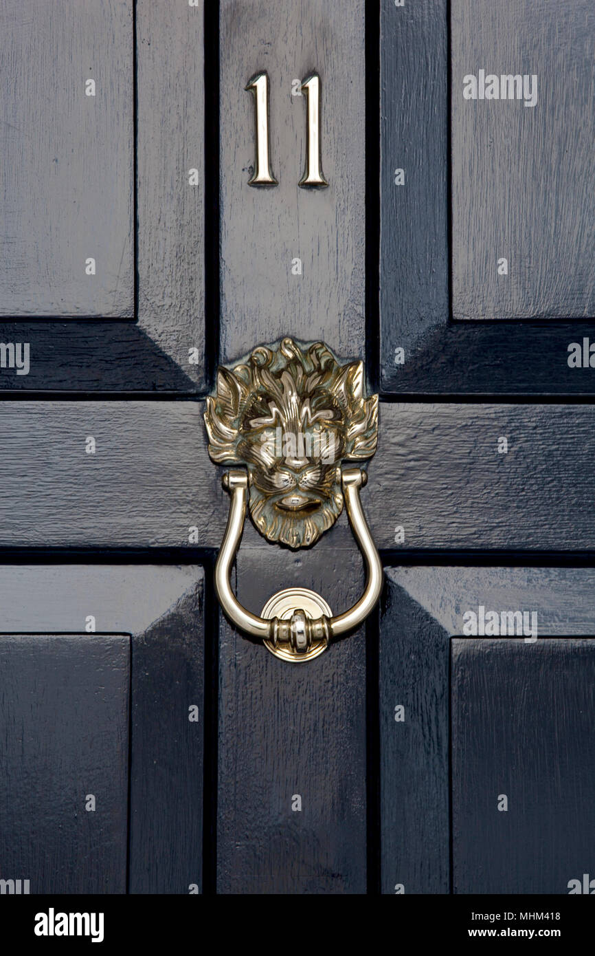 Nahaufnahme der alten schwarzen Holztür mit einem großen Messing Türklopfer in der Form eines Löwen und die Nummer 11 auf der Tür Stockfoto