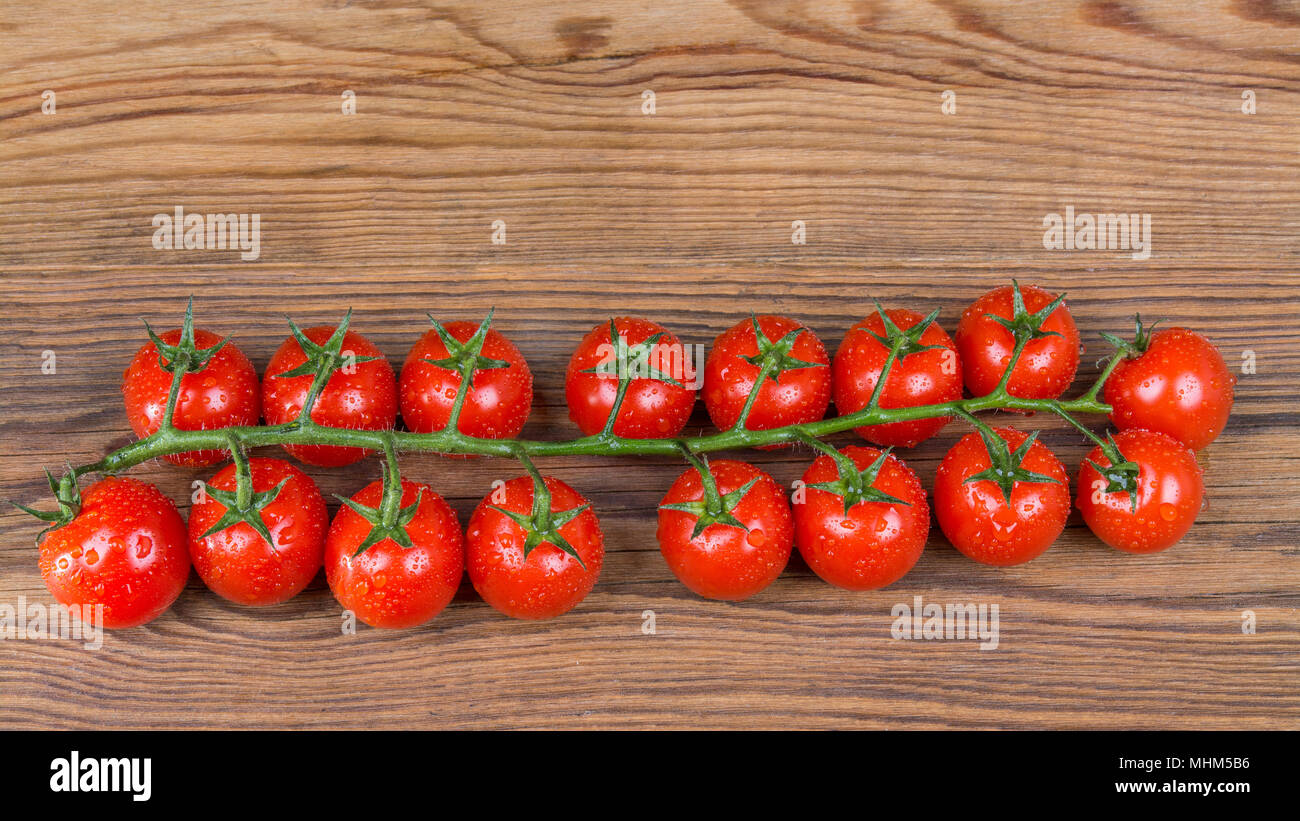 Bündel frische Kirschtomaten auf Holz- Hintergrund. Gewaschen saftige Bio Gemüse voller Vitamine und Antioxidantien mit Wassertröpfchen. Stockfoto