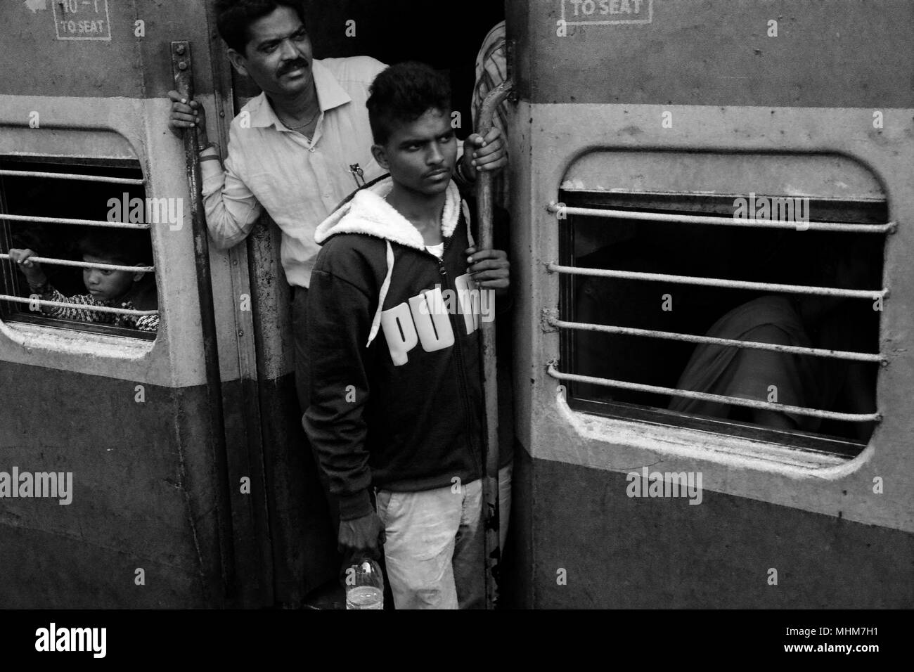 Zwei Männer gefährlich heraus hängen von der Tür in Erwartung Ihrer Ankunft am Zielort, Indien Stockfoto
