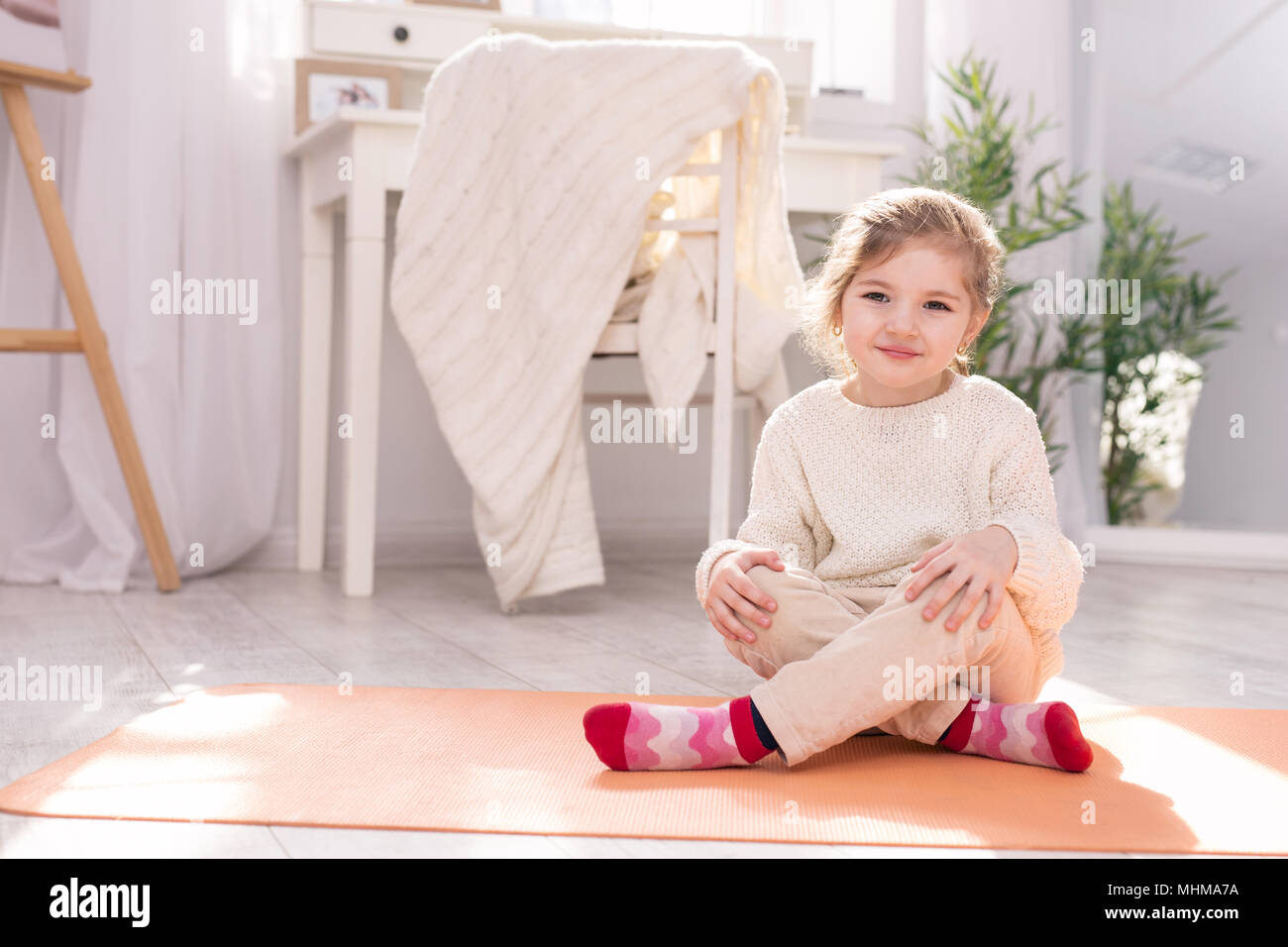 Adorable Kind sitzen auf dem Teppich Stockfoto