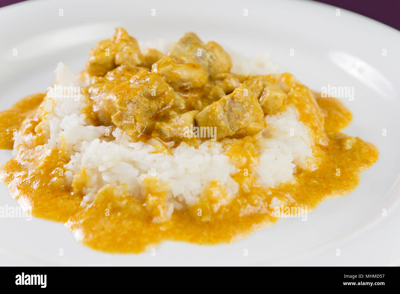 Einfaches Gericht aus Indien. Chicken Korma. Huhn auf einem mild gewürzt Coconut cremige Soße mit Reis auf weiße Platte serviert. Stockfoto