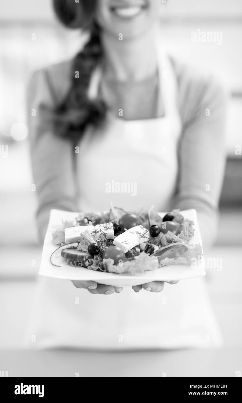 Closeup auf junge Hausfrau zeigt griechischen Salat Stockfoto