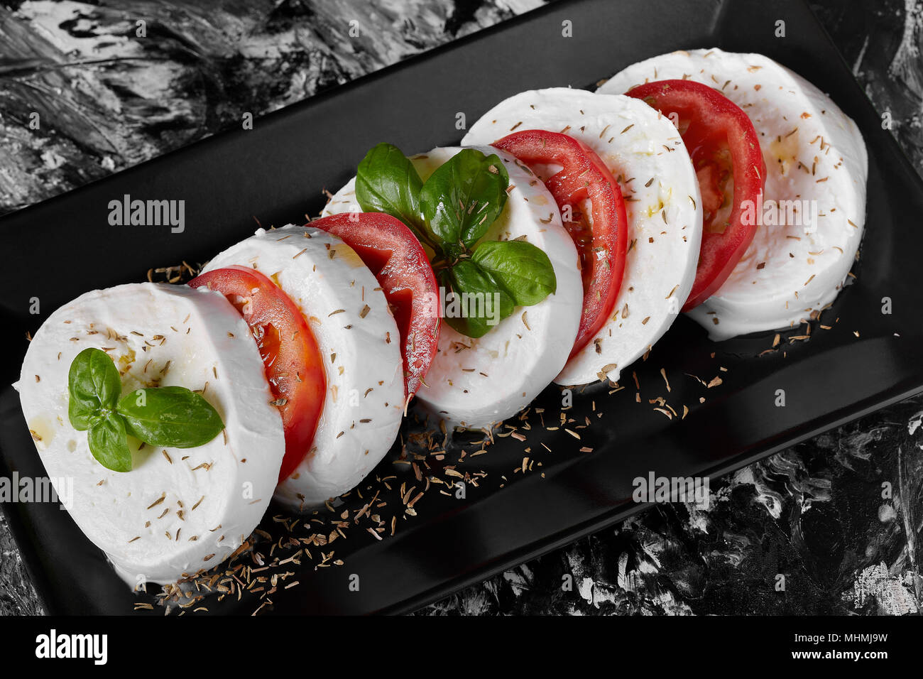 Italienisch typische Platte namens Caprese mit frischem Buffalo Mozzarella,  Tomaten, Basilikum, Olivenöl Stockfotografie - Alamy