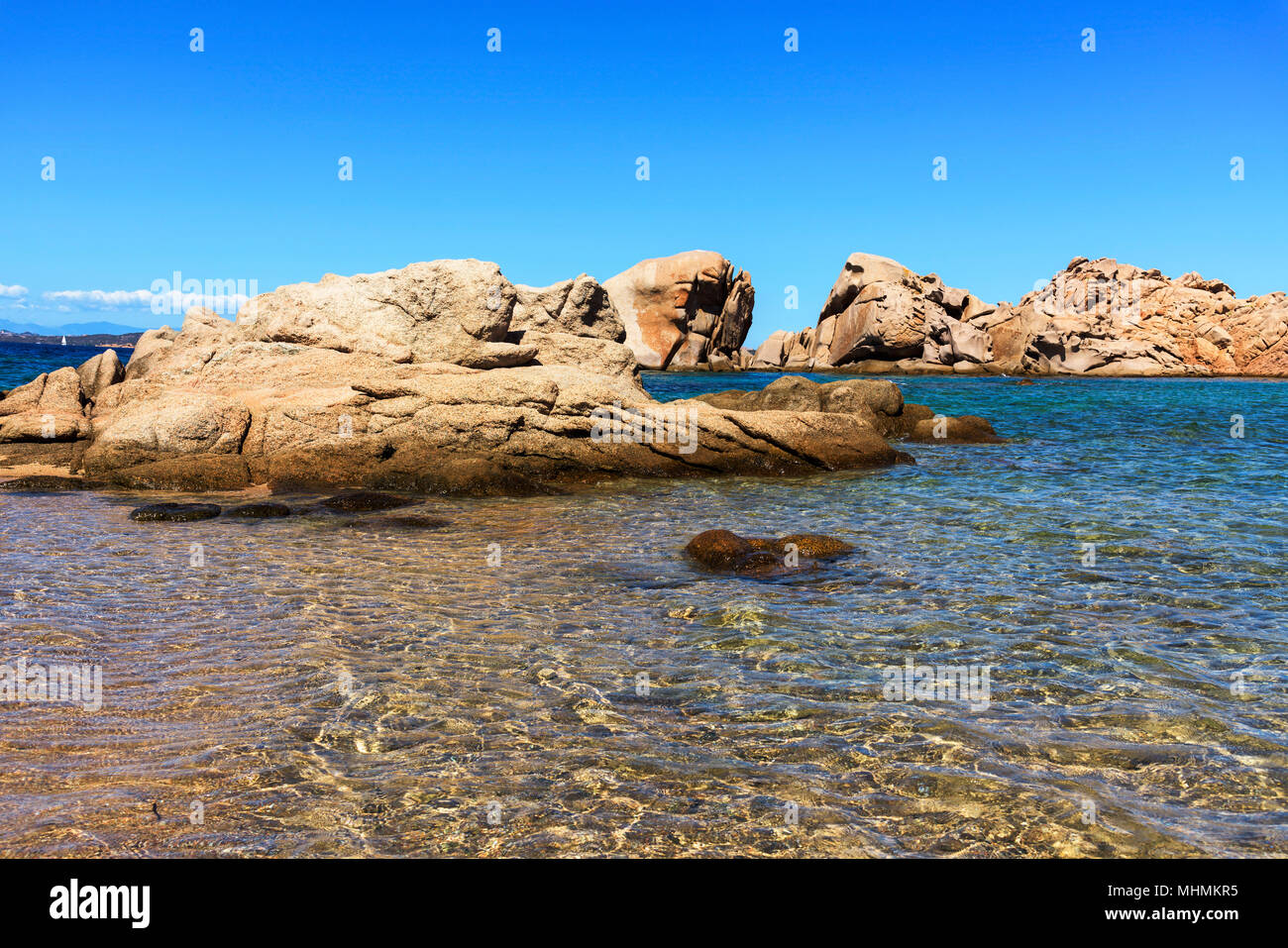 Ein Blick auf das klare Wasser des Mittelmeers und eine Gruppe von Felsformationen in einem ruhigen Strand an der Küste von Baja Sardinia, in der berühmten Costa Stockfoto