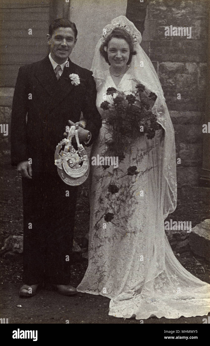 Ein frisch verheiratetes Paar für die Kamera außerhalb einer Kirche darstellen. Datum: C 1945 Stockfoto