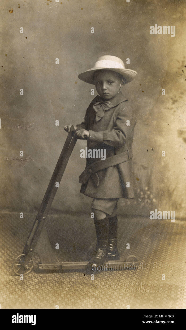 Ein kleiner Junge stellt für sein Foto mit einem frühen scooter. Datum: 1900 Stockfoto