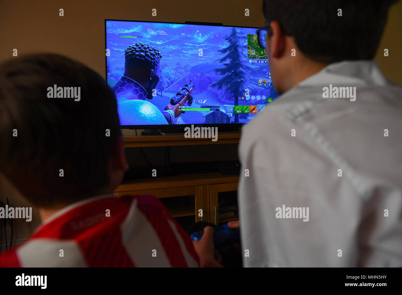 Ein teenager Boy spielt die Hit computer spiel Fortnite auf einem großen TV auf einer Playstation 4-Konsole. Stockfoto