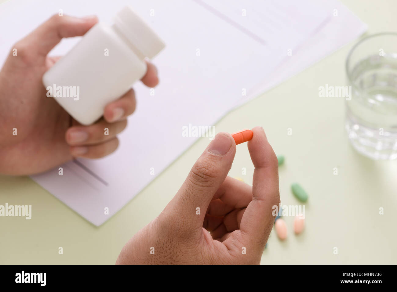 Ansicht von oben in die Hand eines Arztes eine Vorschrift schreiben. Eine Pille, die Flasche und Stethoskop sind auch auf den Schreibtisch. Stockfoto