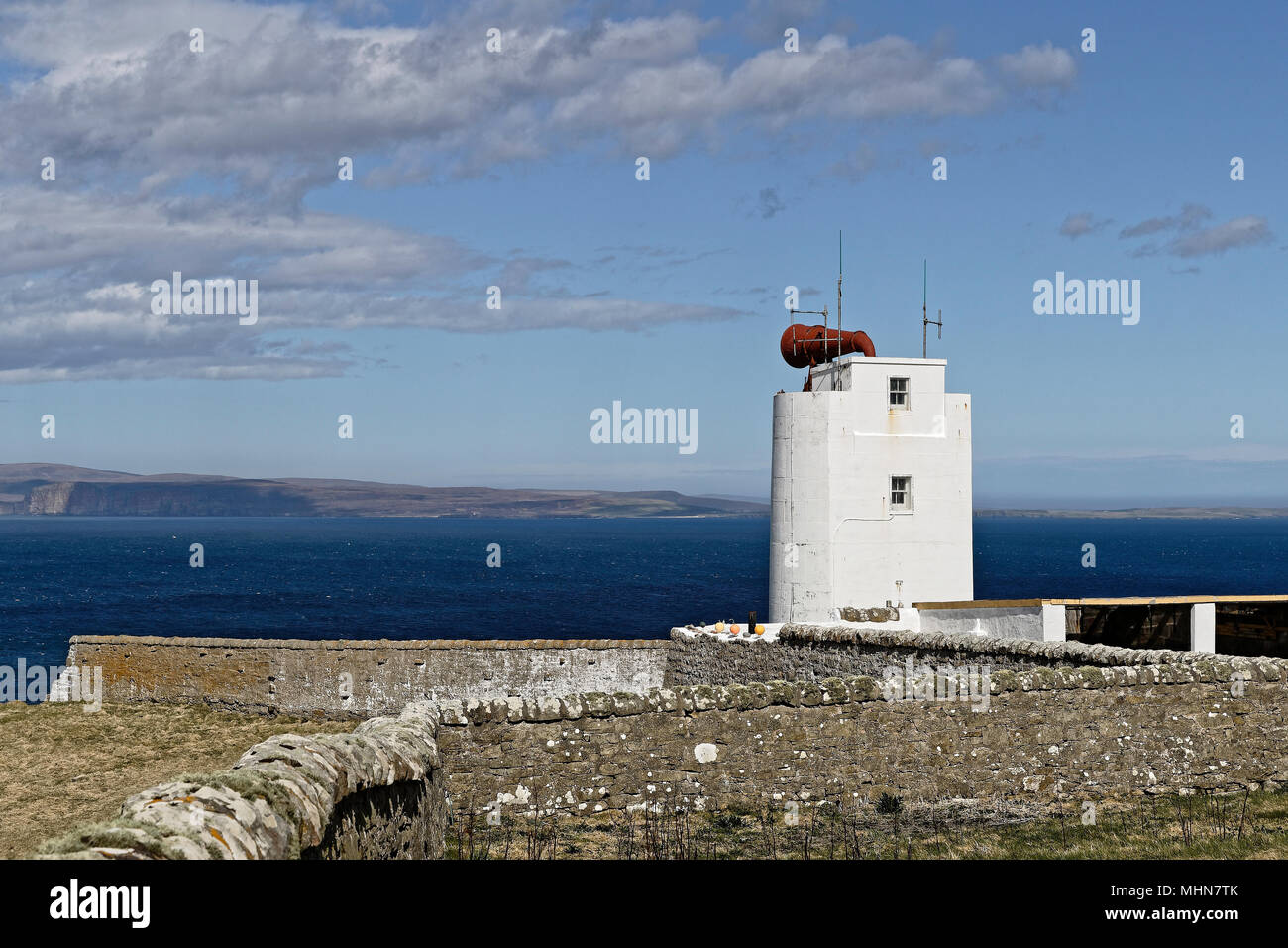 Dunnett Head Lighthouse an der UKs nördlichste Punkt mit den Orkney Inseln im Hintergrund Stockfoto