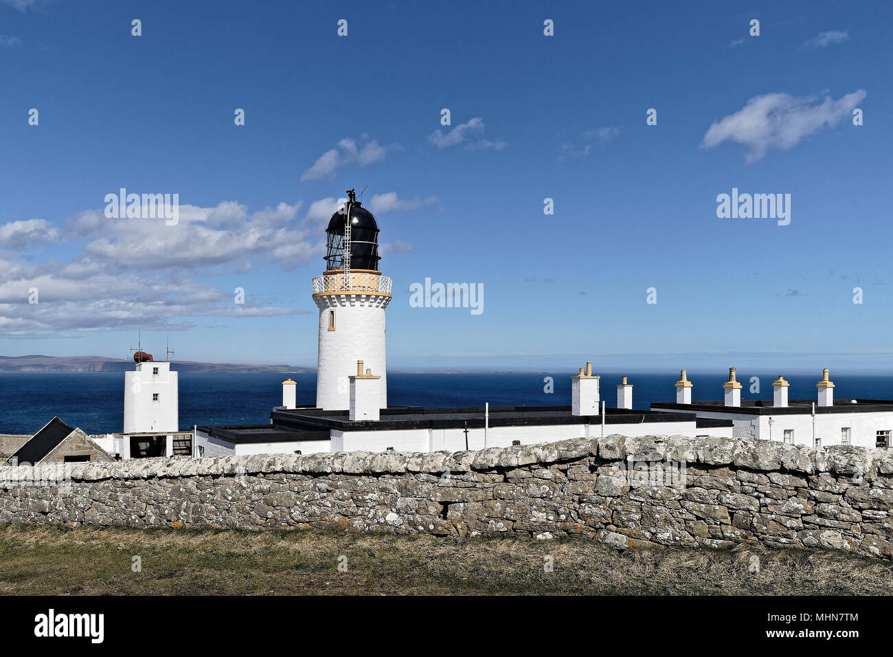 Dunnett Head Lighthouse an der UKs nördlichste Punkt mit den Orkney Inseln im Hintergrund Stockfoto