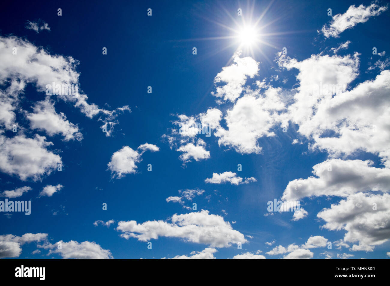 Blauer Himmel mit weißen flauschigen Wolken und Sonne Stockfoto