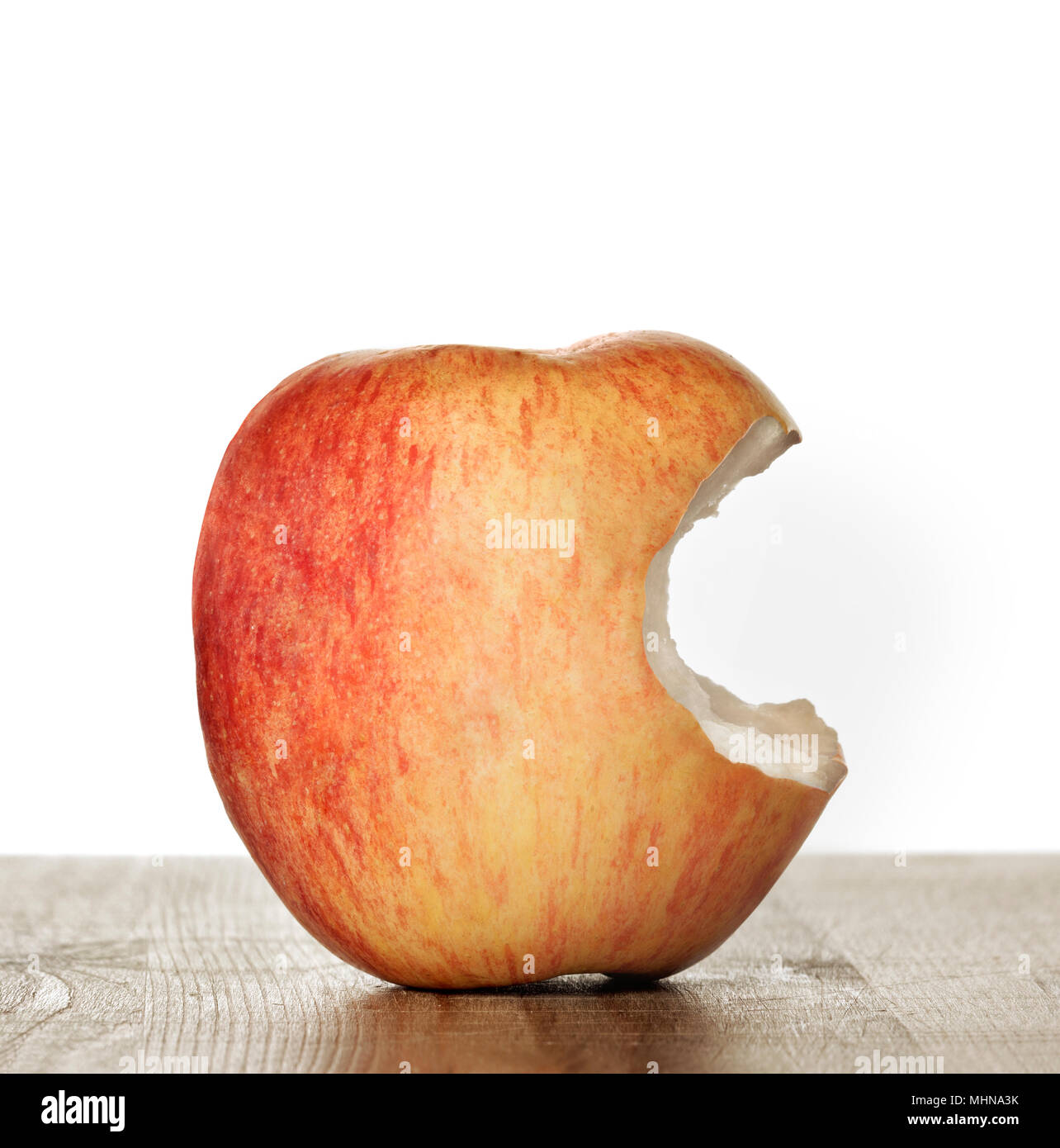 Gebissen Apple auf einem Holztisch und weißem Hintergrund Stockfoto